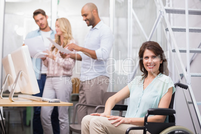 Woman in wheelchair smiling at camera with team behind her