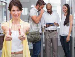 Woman giving thumbs up at camera in front of her colleagues
