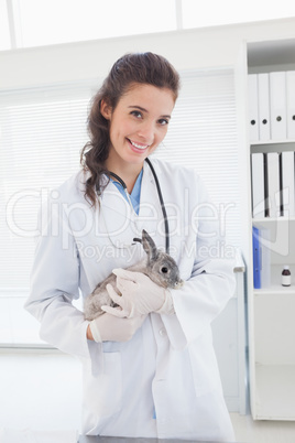 Smiling vet with a rabbit in her arms