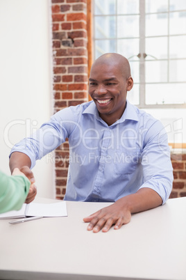 Casual business people shaking hands at desk