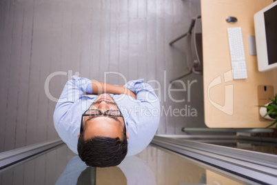 Thoughtful businessman standing against glass wall at office
