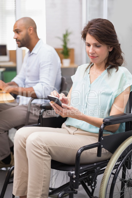 Businesswoman in wheelchair texting on phone