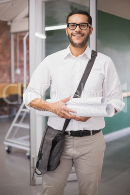 Casual architect smiling at camera holding blueprints