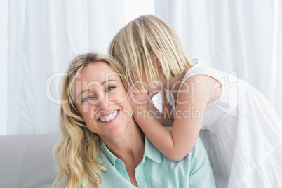 Mother sitting with her daughter whispering a secret