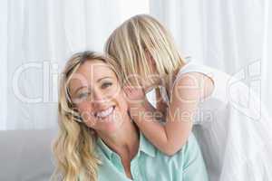 Mother sitting with her daughter whispering a secret