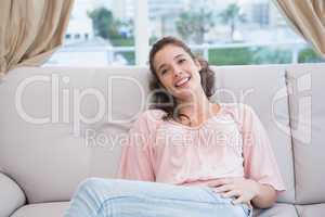 Pretty brunette smiling at camera on the couch