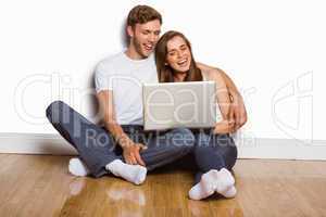 Young couple using laptop on floor