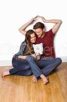 Couple sitting on floor with piggy bank
