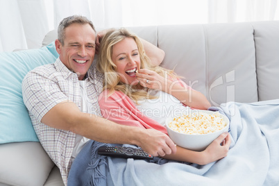 Couple eating popcorn while watching television