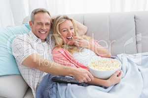Couple eating popcorn while watching television