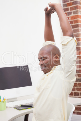 Casual businessman stretching at his desk