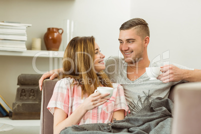 Cute couple relaxing on couch with coffee