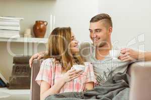 Cute couple relaxing on couch with coffee