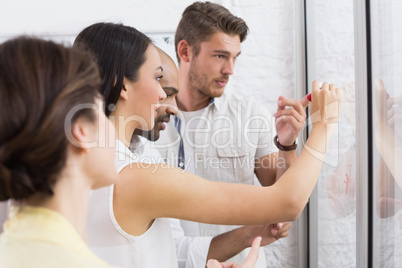 Colleagues watching thinking businesswoman writing