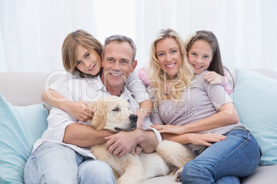 Cute family relaxing together on the couch with their dog