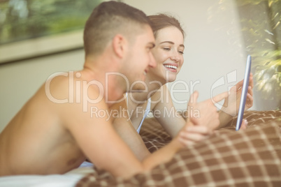 Cute couple using tablet pc in bed