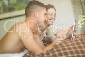 Cute couple using tablet pc in bed