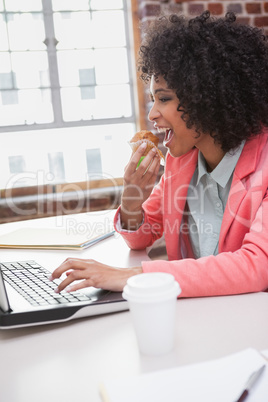 Casual businesswoman eating a muffin while working