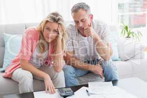 Worried couple calculating bills on the couch
