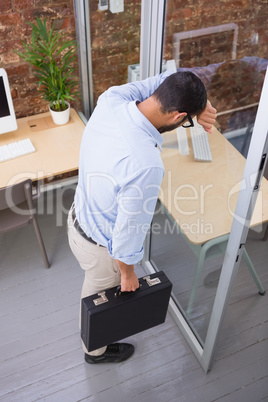 Thoughtful businessman standing against glass wall