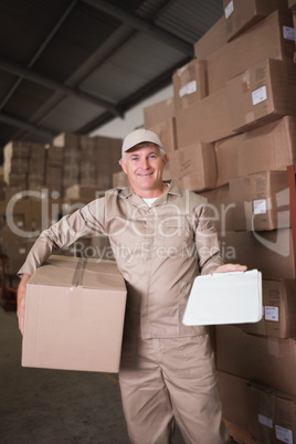 Delivery man with box and clipboard in warehouse