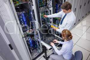 Team of technicians using digital cable analyser on servers