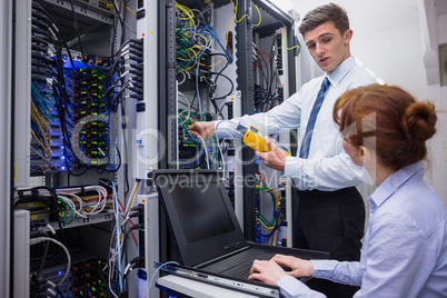 Team of technicians using digital cable analyser on servers