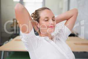 Businesswoman with hands behind head and eyes closed in office