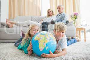 Siblings looking at globe on the floor