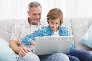 Father with son sitting on the couch using laptop