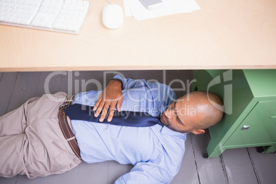 Businessman sleeping under desk