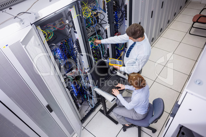 Team of technicians using digital cable analyser on servers