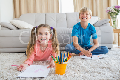 Happy siblings colouring on the rug