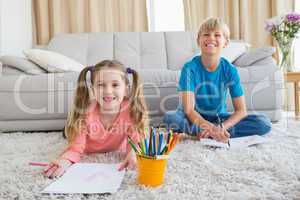 Happy siblings colouring on the rug