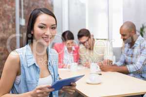 Smiling woman holding tablet in front of her colleague