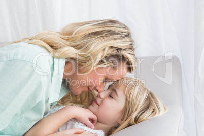 Mother and daughter rubbing noses on sofa