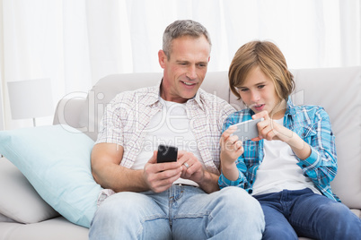 Son showing something on his mobile phone to his father
