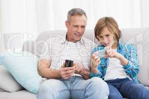 Son showing something on his mobile phone to his father