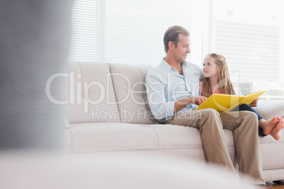 Casual father and daughter looking at photo album