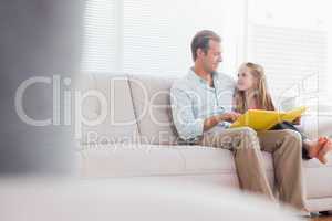 Casual father and daughter looking at photo album