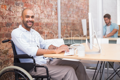 Smiling businessman in wheelchair working at his desk