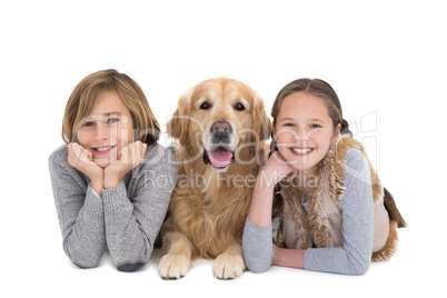 Portrait of happy siblings lying on the floor with their dog