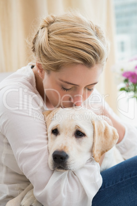 Happy blonde cuddling with puppy on sofa