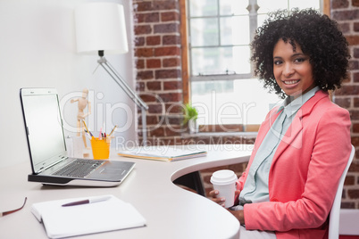 Happy casual businesswoman sitting at desk