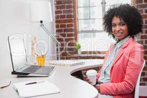 Happy casual businesswoman sitting at desk