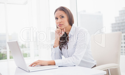 Thoughtful businesswoman using laptop at her desk