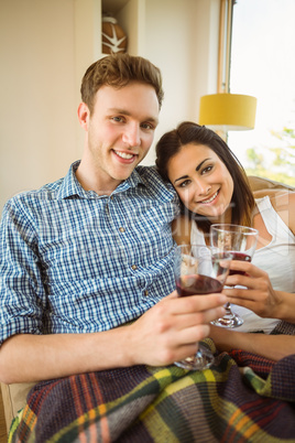 Happy young couple relaxing on the couch with red wine