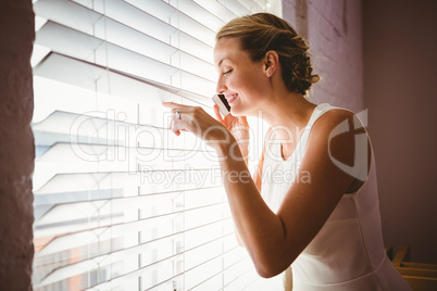 Casual businesswoman using mobile phone while looking through bl