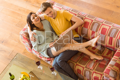 Young couple cuddling on the couch with laptop