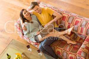 Young couple cuddling on the couch with laptop